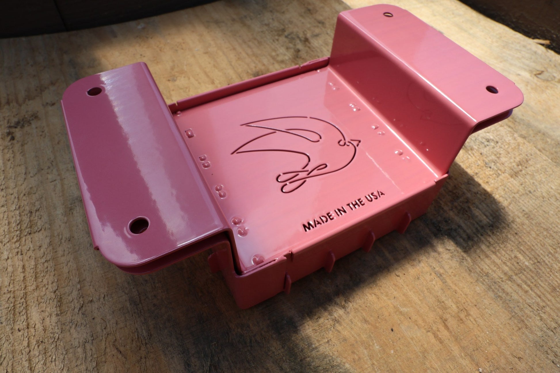 Three quarter view of the pink Nano 25 hand soil blocker on a weathered wood bench