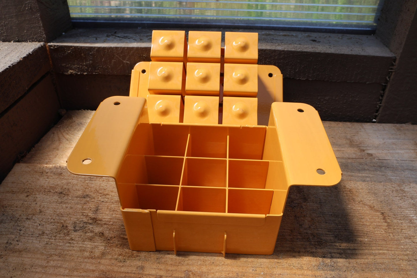 Nano 9 soil blocker in tangerine, open to show the 9-cell grid and the block-forming plate