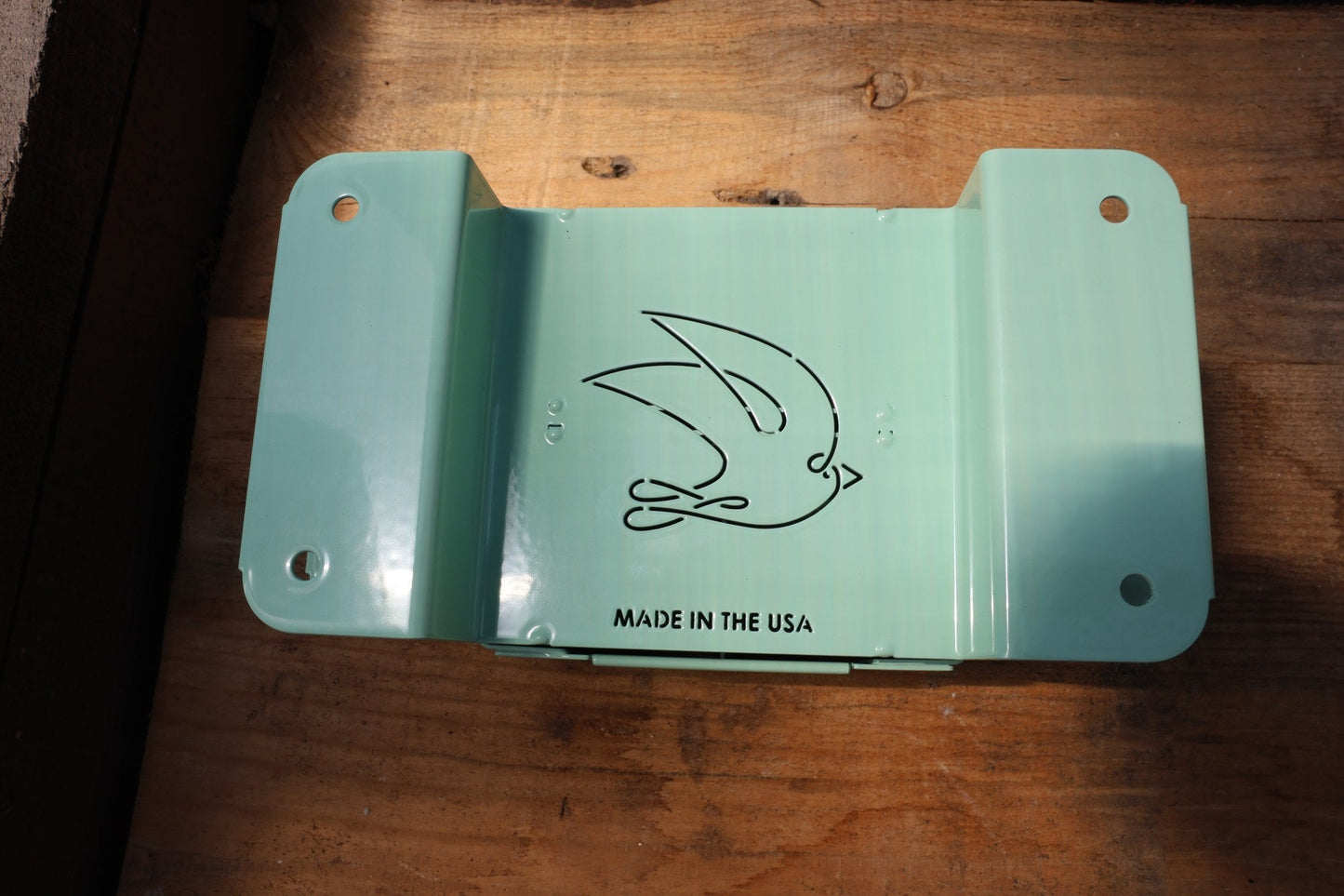 Green Nano 4 hand soil blocker closed, on a weathered wood bench