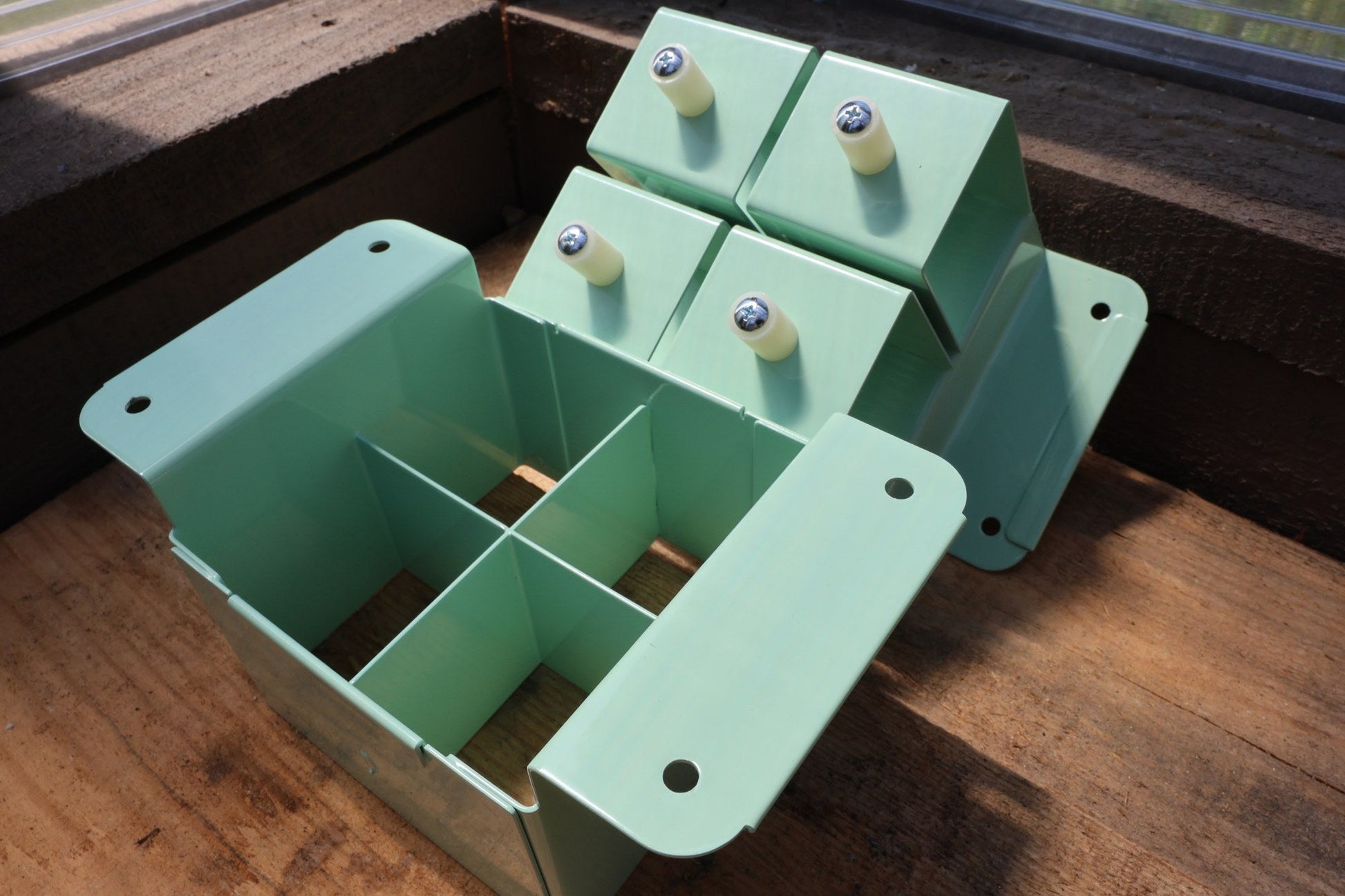 Nano 4 soil blocker in green, open to show the 4-cell grid and the dibble block-forming plate